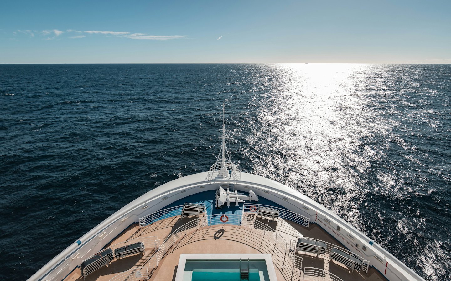 White cruise ship sailing across the deep blue ocean.